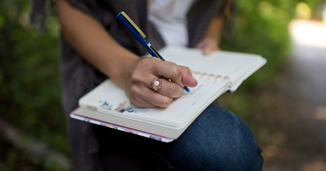 Desktop women for one share page banner image women writing in a notebook in the forest